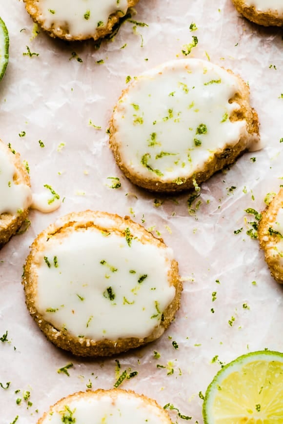 Key Lime cookies in a close-up photo topped with glaze and lime zest. 