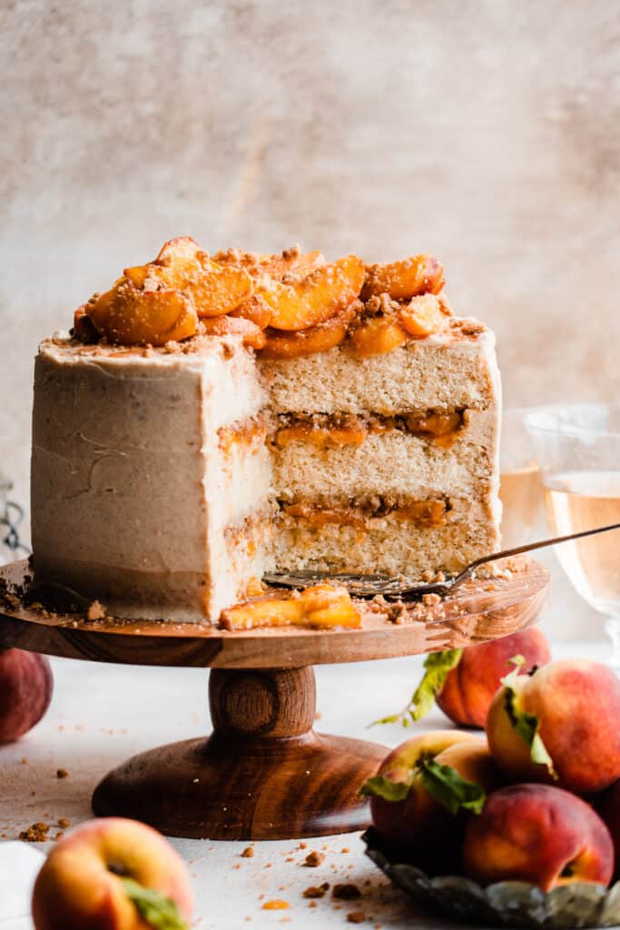 The sliced peach cobbler cake on a cake stand topped with peach slices.