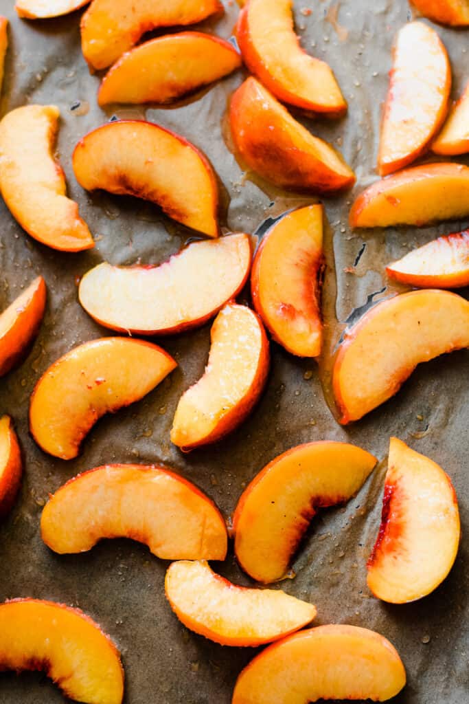 Uncooked peach slices on a baking sheet. 