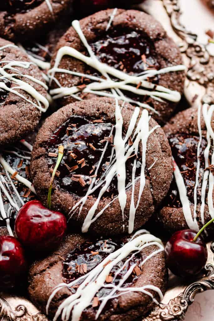 A close-up of a black forest cookie on top of the pile, with cherries scattered around.
