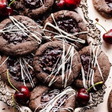 Black forest cookies in a vintage metal tray with cherries scattered around.