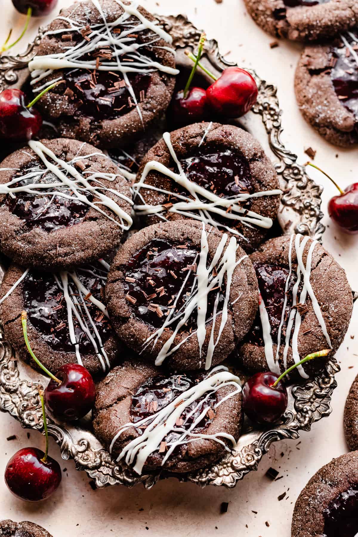 Black forest cookies in a vintage metal tray with cherries scattered around.