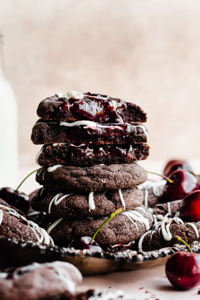 A stack of black forest cookies on a vintage metal tray, with the top ones broken open to reveal fudgy insides.