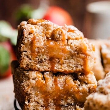 A stack of two slices of apple crumb cake drizzled with caramel, on a wire rack.