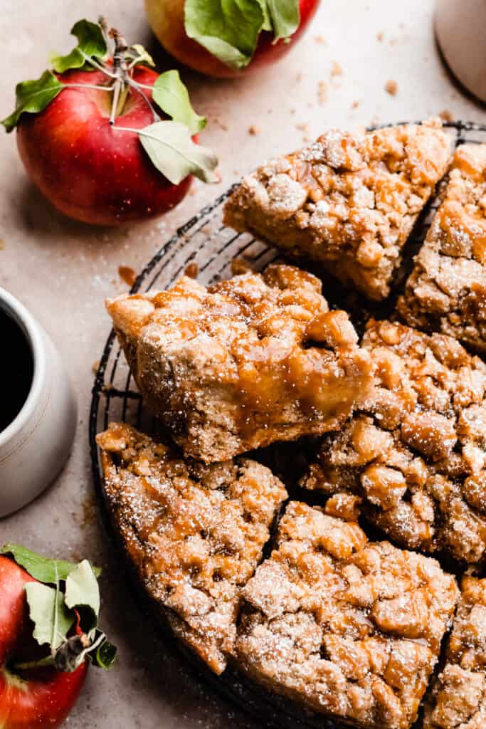Slices of apple crumb cake on a wire rack, drizzled with caramel sauce. 