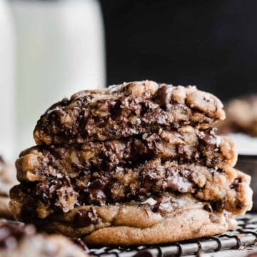 A stack of broken open cookies, showing their gooey insides with chocolate puddles.