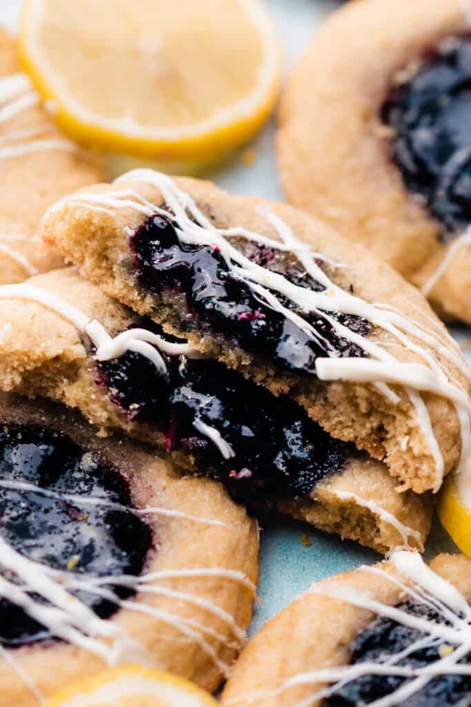 A close-up of two halves of a white chocolate-drizzled lemon blueberry sugar cookie.