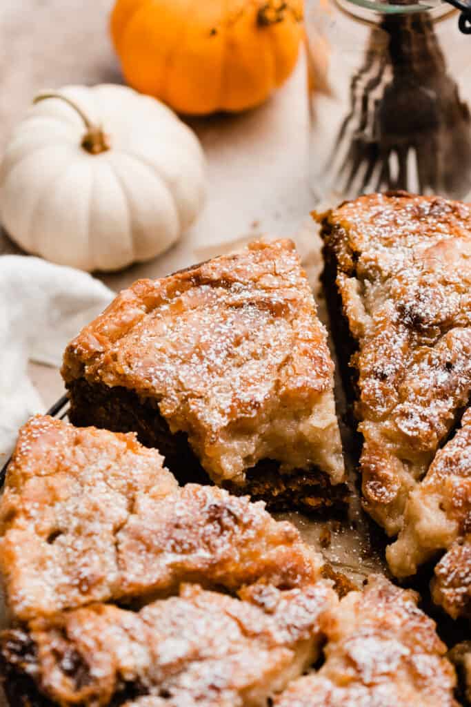 A close-up on a slice of pumpkin gooey butter cake with a bite missing.