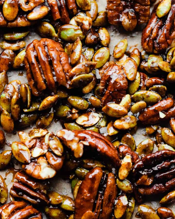 A close-up of candied pecans and pepitas on a baking sheet.