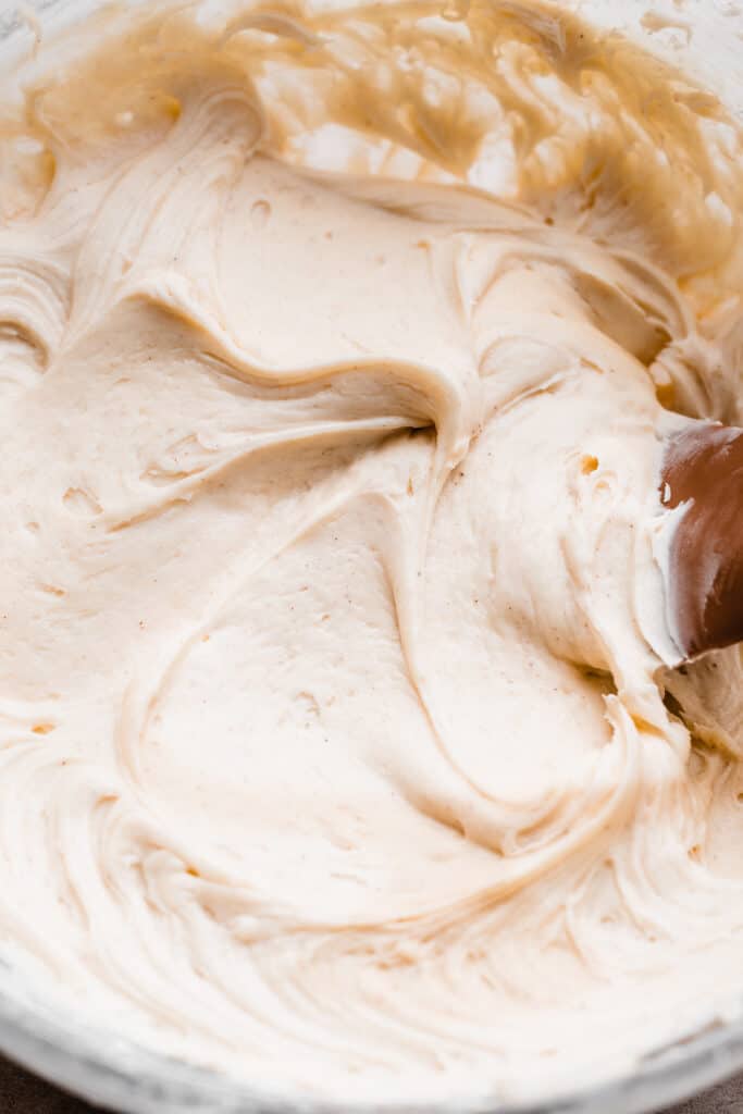 A close-up on a bowl of cinnamon cream cheese frosting.