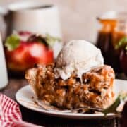 A slice of apple pie with caramel sauce and a scoop of ice cream.