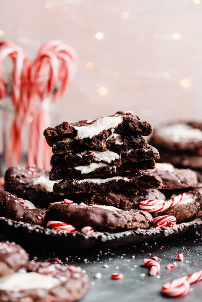 A straight on view of a stack of the broken open cookies with twinkle lights and candy canes in the background.