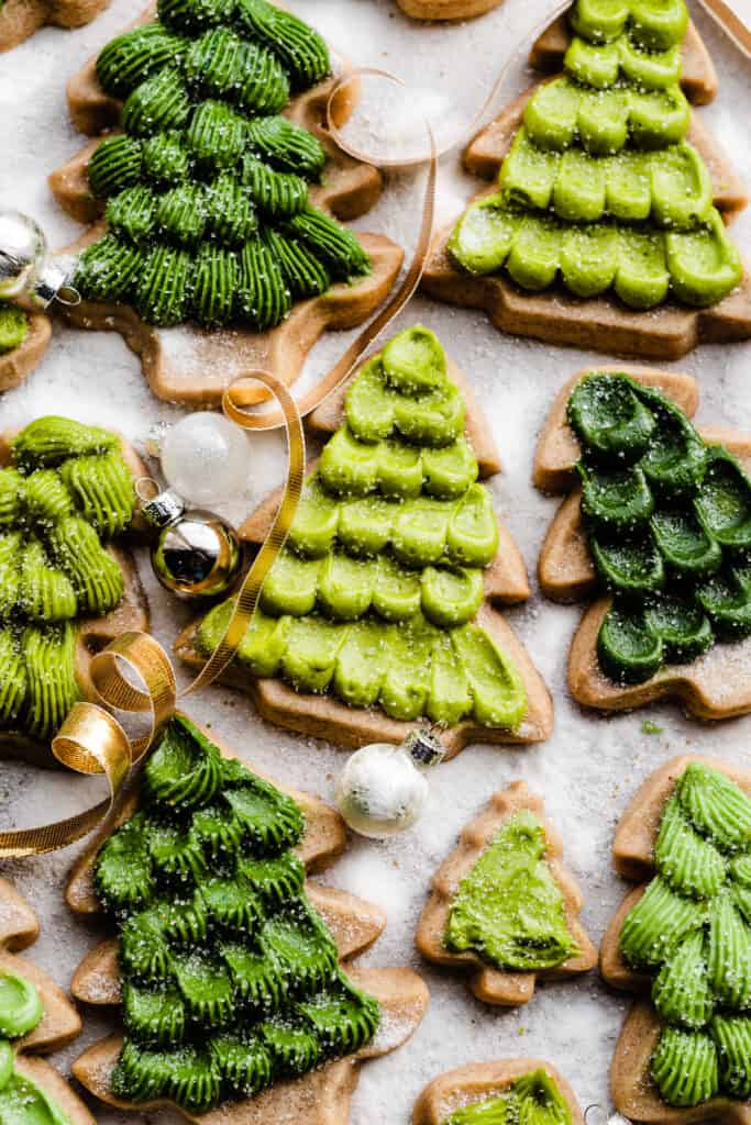 Honey cookies decorated like christmas trees in various shapes and colors, on a sugary backdrop.