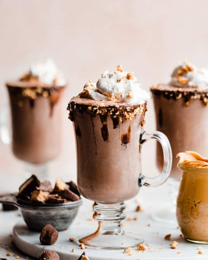 Milkshakes in glasses with chocolate dipped rims and whipped cream on top.