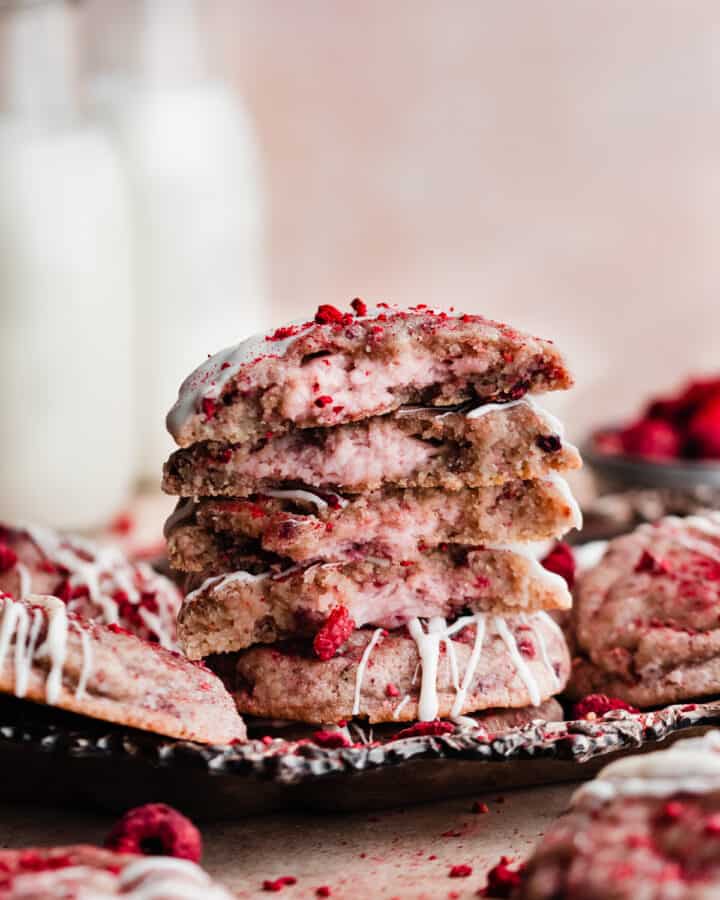 Thick, soft raspberry sugar cookies are stuffed with a creamy raspberry cheesecake filling and drizzled with white chocolate. These cookies are absolutely packed with flavor and can be made ahead & frozen until ready to bake! #raspberry #raspberrycookies #cheesecake #cheesecakecookies #raspberrycheesecake #whitechocolate #cookierecipes #christmascookies #valentinesdesserts #springdesserts #bluebowlrecipes | bluebowlrecipes.com