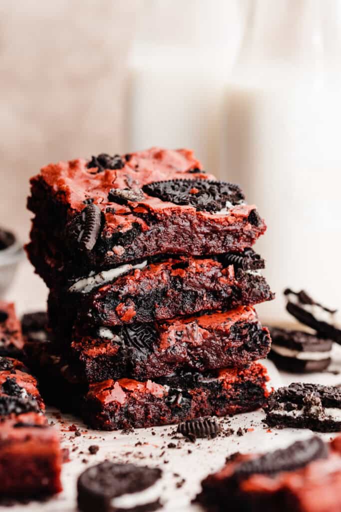 A stack of red velvet brownies with milk bottles in the background.