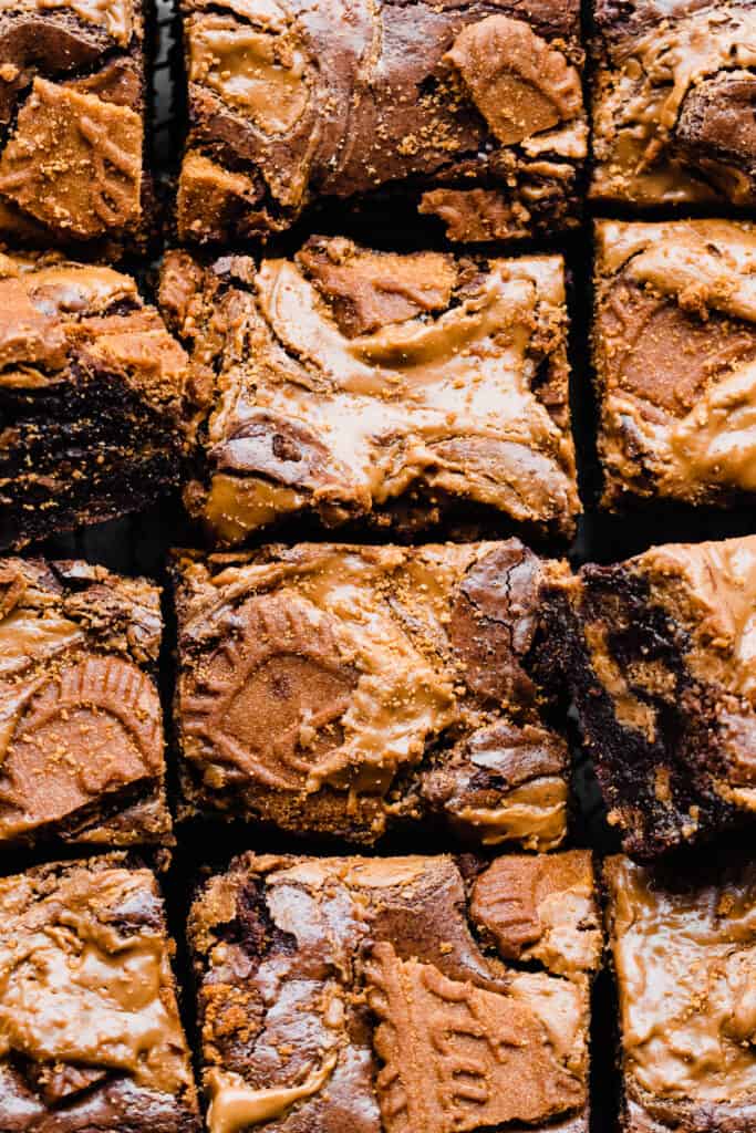 A bird's eye view of the sliced brownies in rows, with visible melty pools of cookie butter and cookie pieces on top.