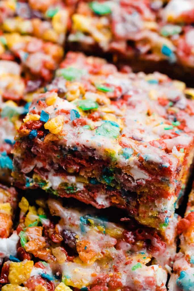 A slice of fruity pebble treat peeking up out of a row of them.