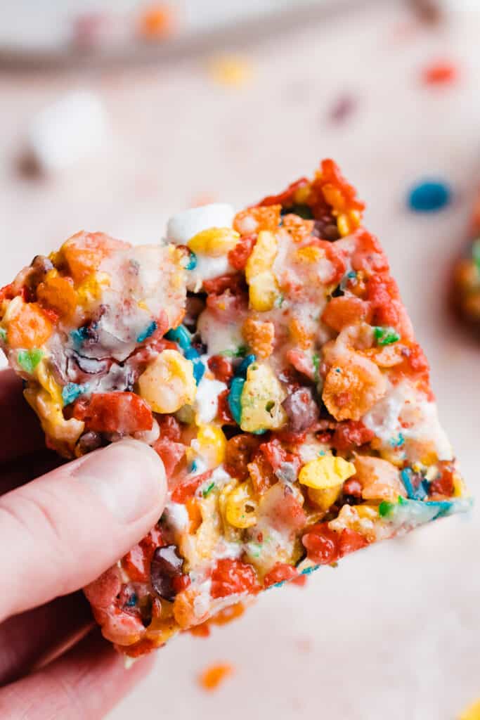 A hand holding up a fruity pebble treat. 