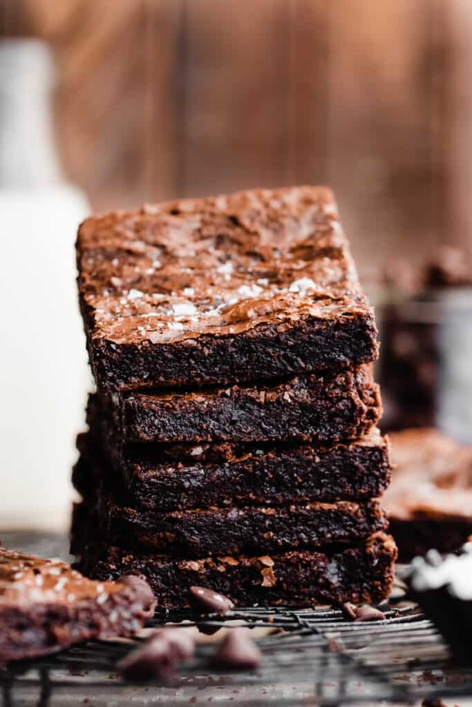 A stack of brownies with milk bottles in the background.
