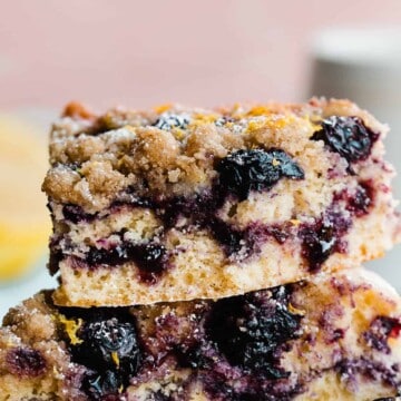 A stack of blueberry lemon coffee cake slices with blueberries and a blueberry jam ripple.