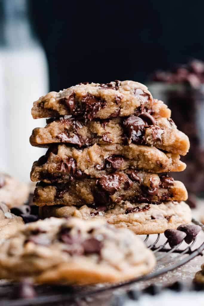 A stack of broken open cookies, showing their gooey insides, studded with melty chocolate chips.