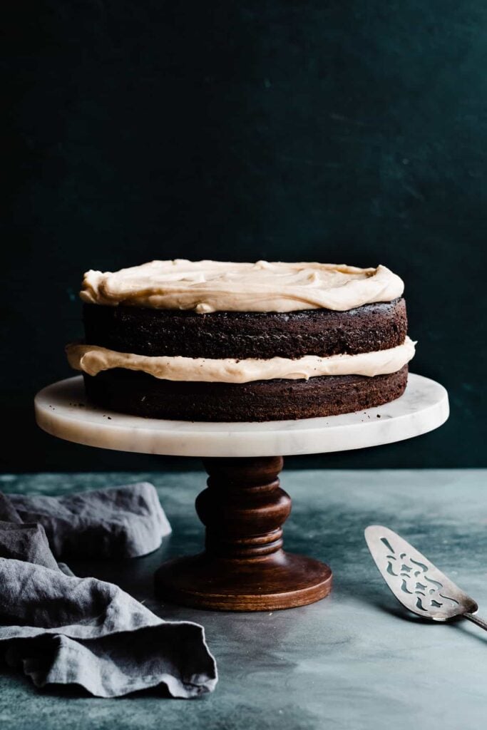 A two layer guinness chocolate cake on a cake stand.