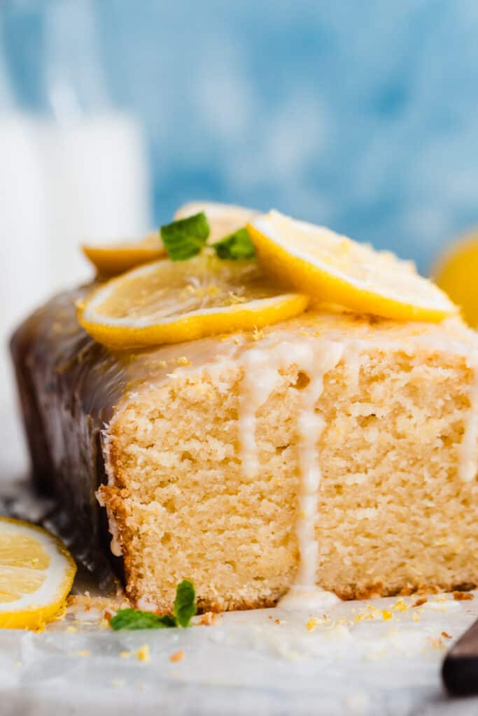 A close-up on lemon loaf cake with the end sliced off, revealing the fluffy, moist texture. 