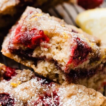 A close-up on a slice of coffee cake with a bite missing, showing the raspberry rippled center and fresh raspberries baked in.
