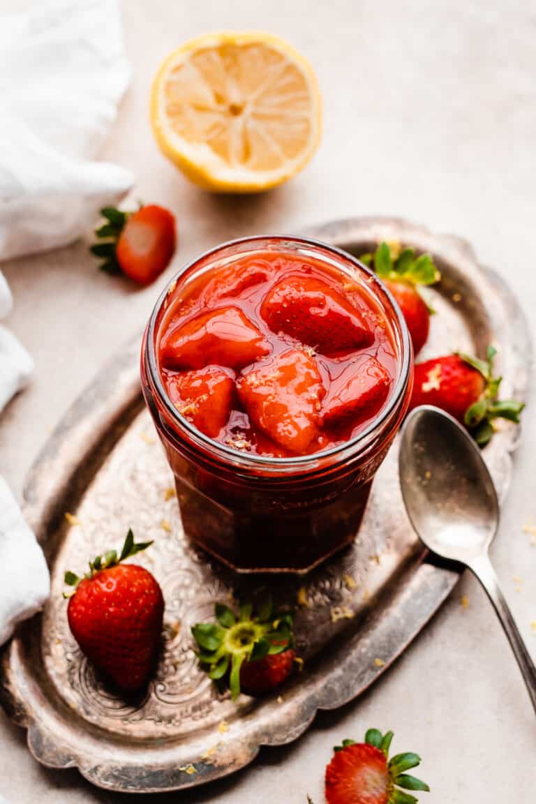 A jar of strawberry compote on a vintage metal tray.