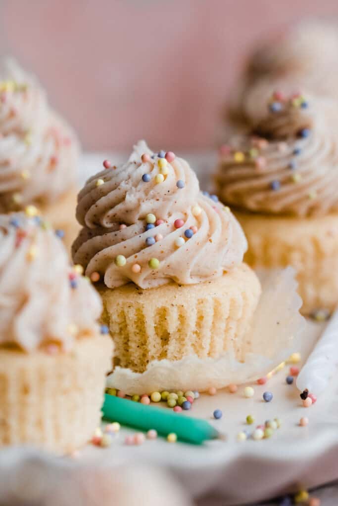 Mini vanilla cupcakes with colorful sprinkles on a fluted plate.
