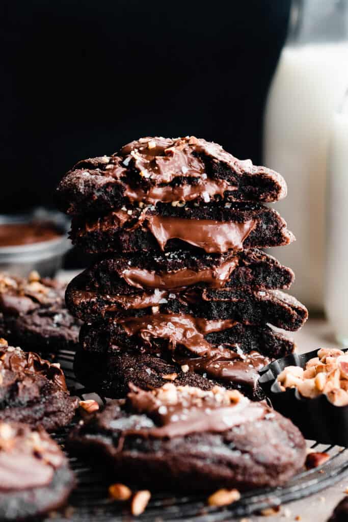A stack of nutella filled chocolate cookie halves, with the nutella spilling out.