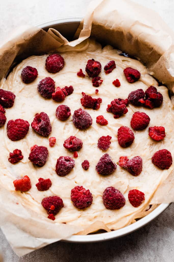 Cake batter in the pan topped with raspberries.