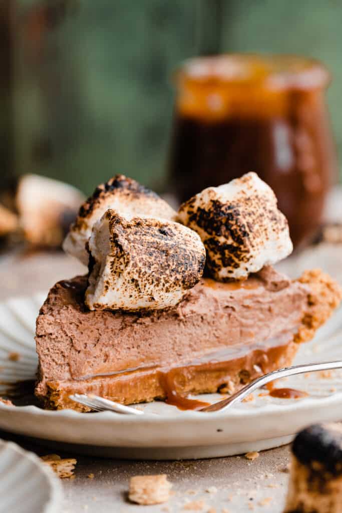 A slice of creamy chocoalte s'mores pie on a plate.