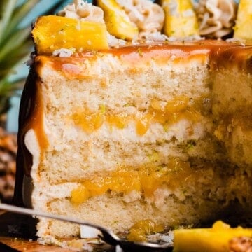 A close-up on the sliced pina colada cake, with coconut frosting and pineapple filling showing.