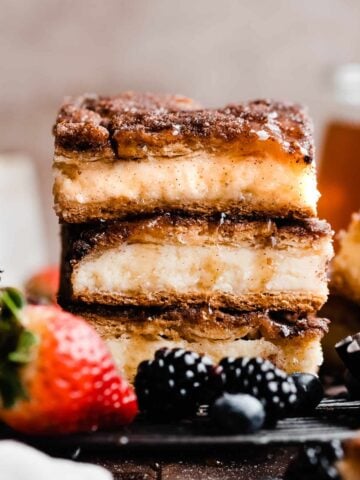 A stack of three sopapilla cheesecake bars drizzled with honey.