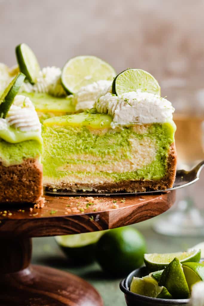 A slice of key lime cheesecake on a cake stand. 