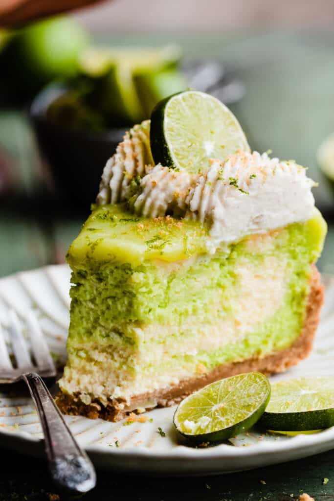 A slice of lime cheesecake with a bite missing.