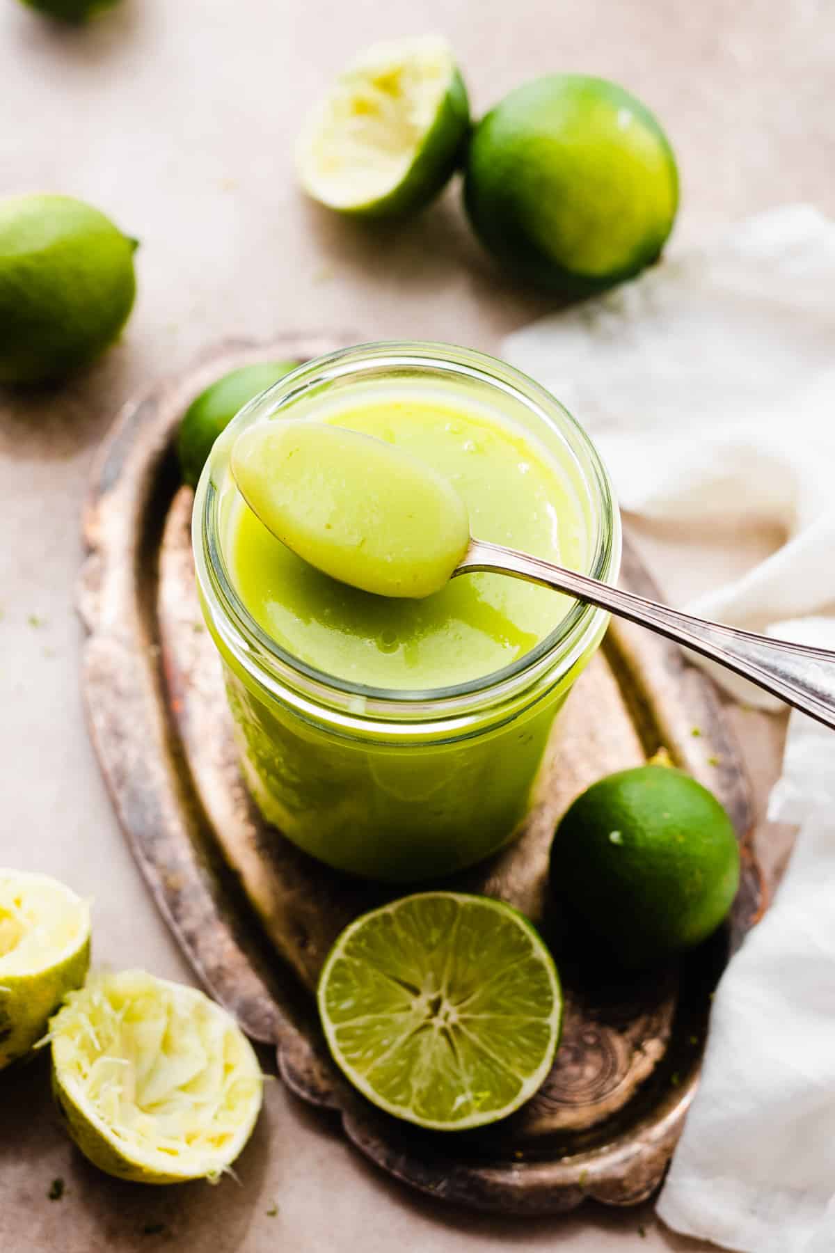 A spoon resting on a jar of bright green lime curd.