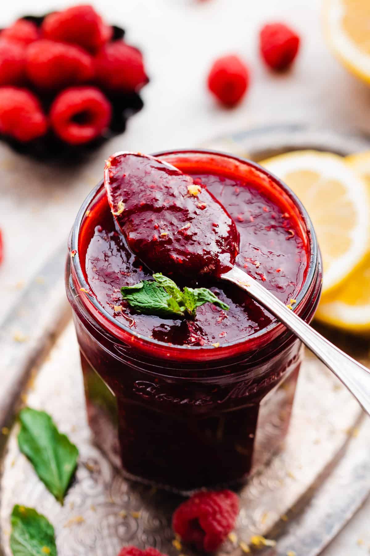A spoonful of raspberry sauce resting on a jar full.