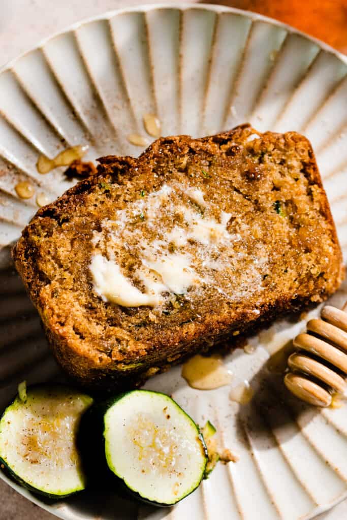 A slice of honey buttered zucchini bread on a plate.
