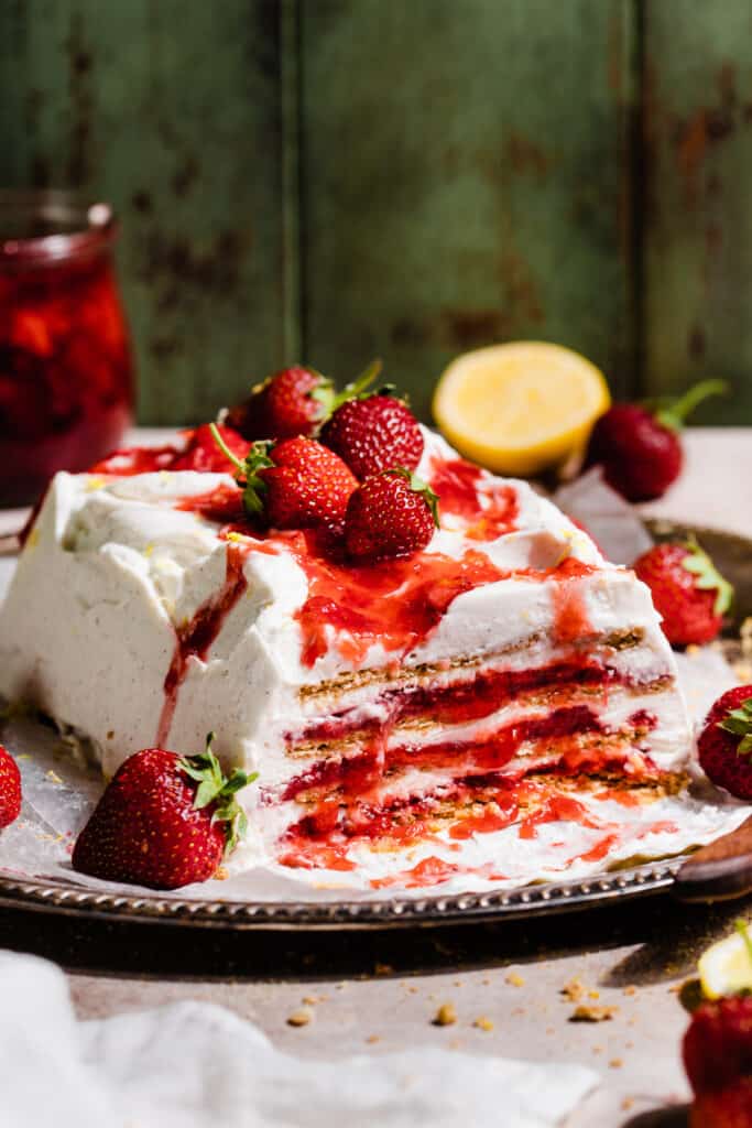 The sliced icebox cake on a platter with strawberries on top.