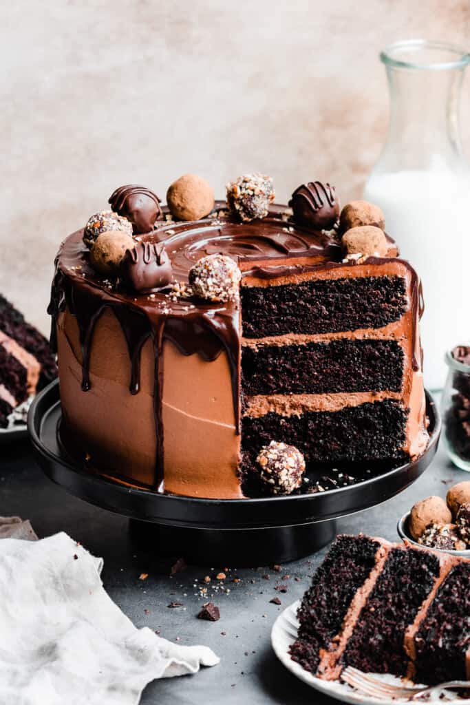 The sliced open chocolate truffle cake topped with chocolate drip and chocolate truffles.