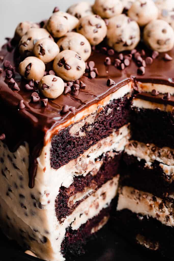 A close-up of the inside of the cake, with visible layers of chocolate cake, edible cookie dough, cookie dough frosting, and chocolate drip.