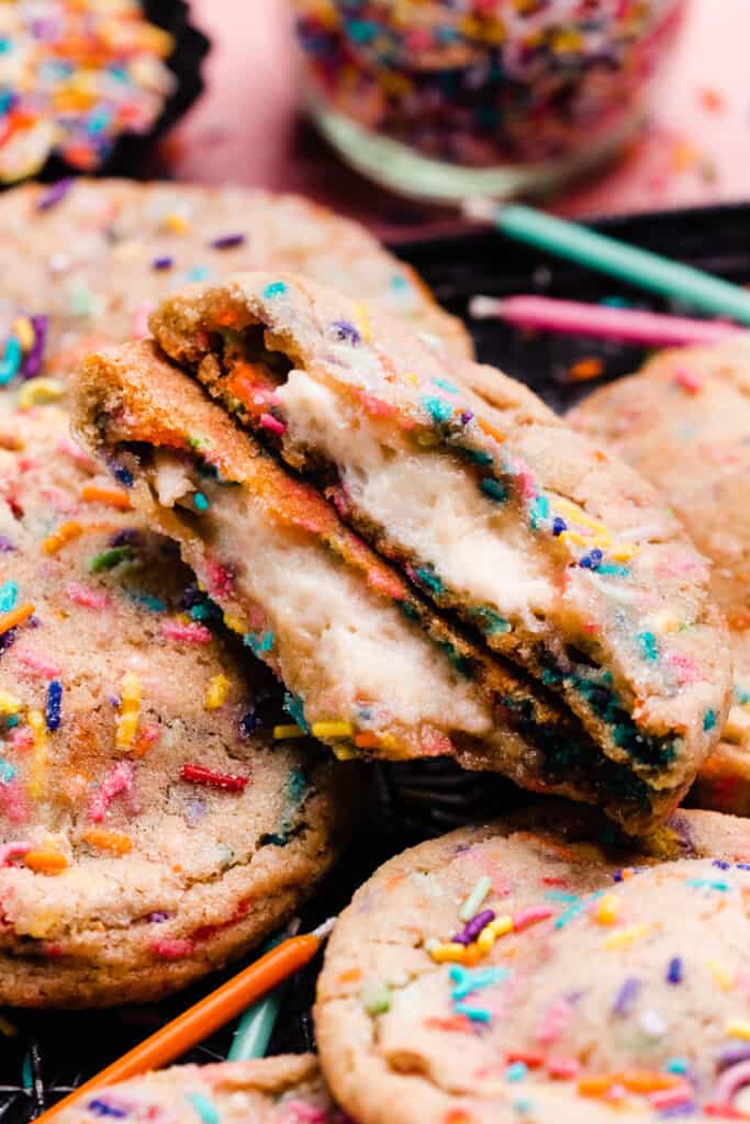 Two halves of funfetti cookie, showing the cheesecake filling inside.