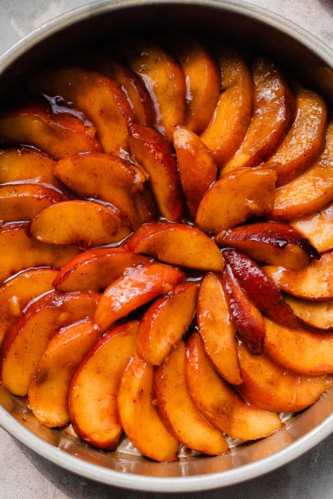 A close-up of the spirals of peach slices in the cake pan.