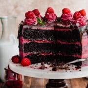 Sliced open chocolate raspberry cake on a cake stand.