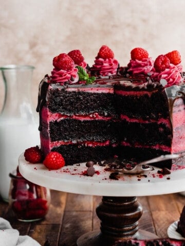 Sliced open chocolate raspberry cake on a cake stand.