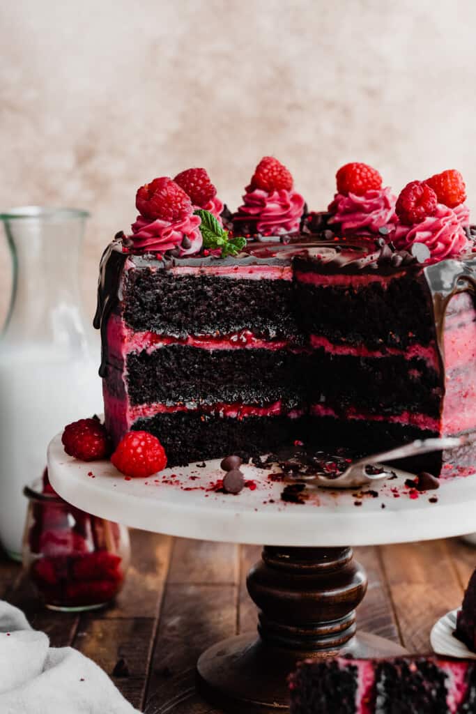 The sliced open raspberry chocolate cake on a cake stand.