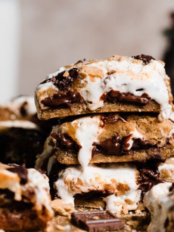 A stack of s'mores bars with the gooey layers of chocolate, caramel, and marshmallow cream showing.